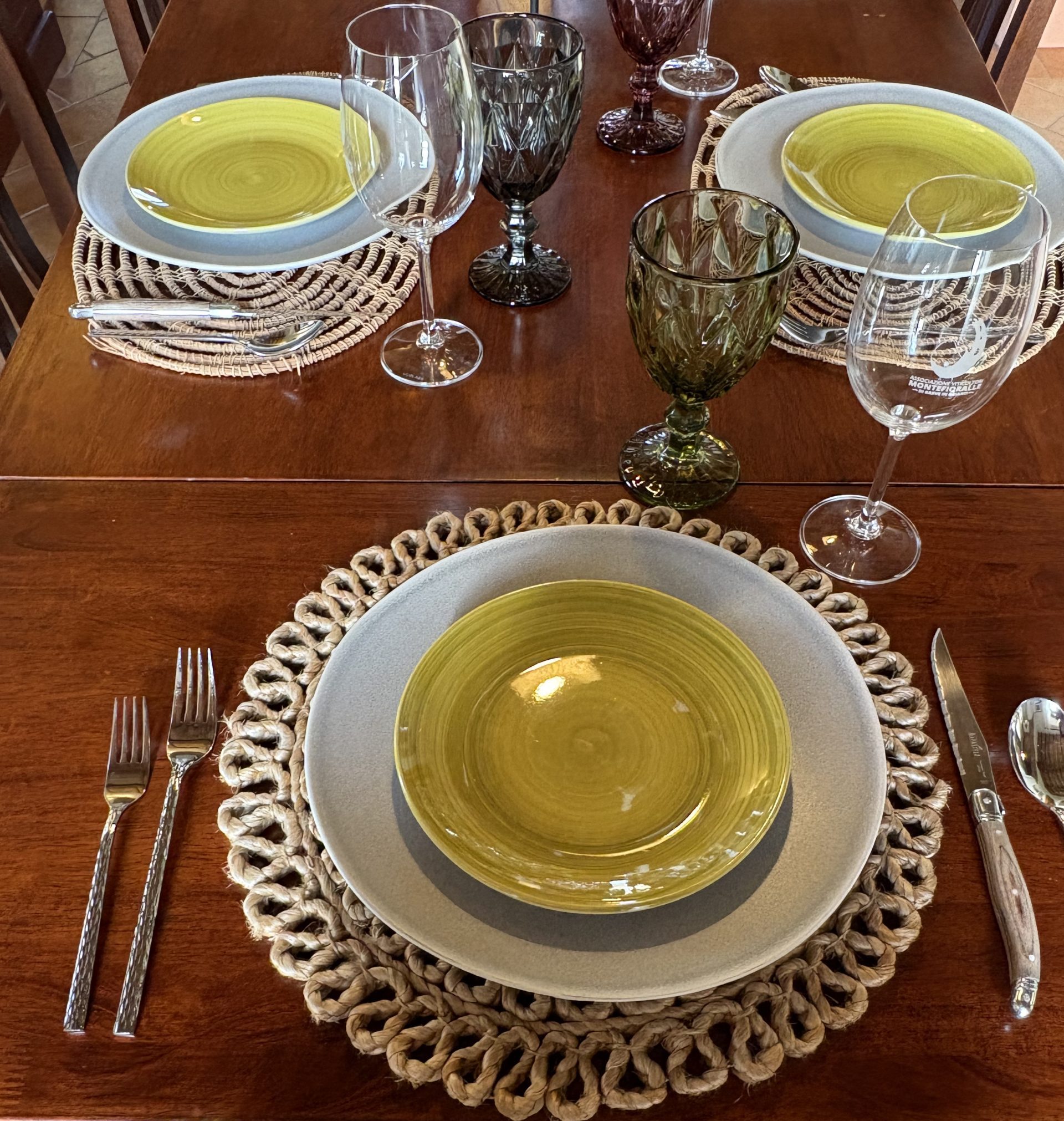 Italian stoneware and pottery dinner plates, hammered silverware, water goblets and wine glasses.