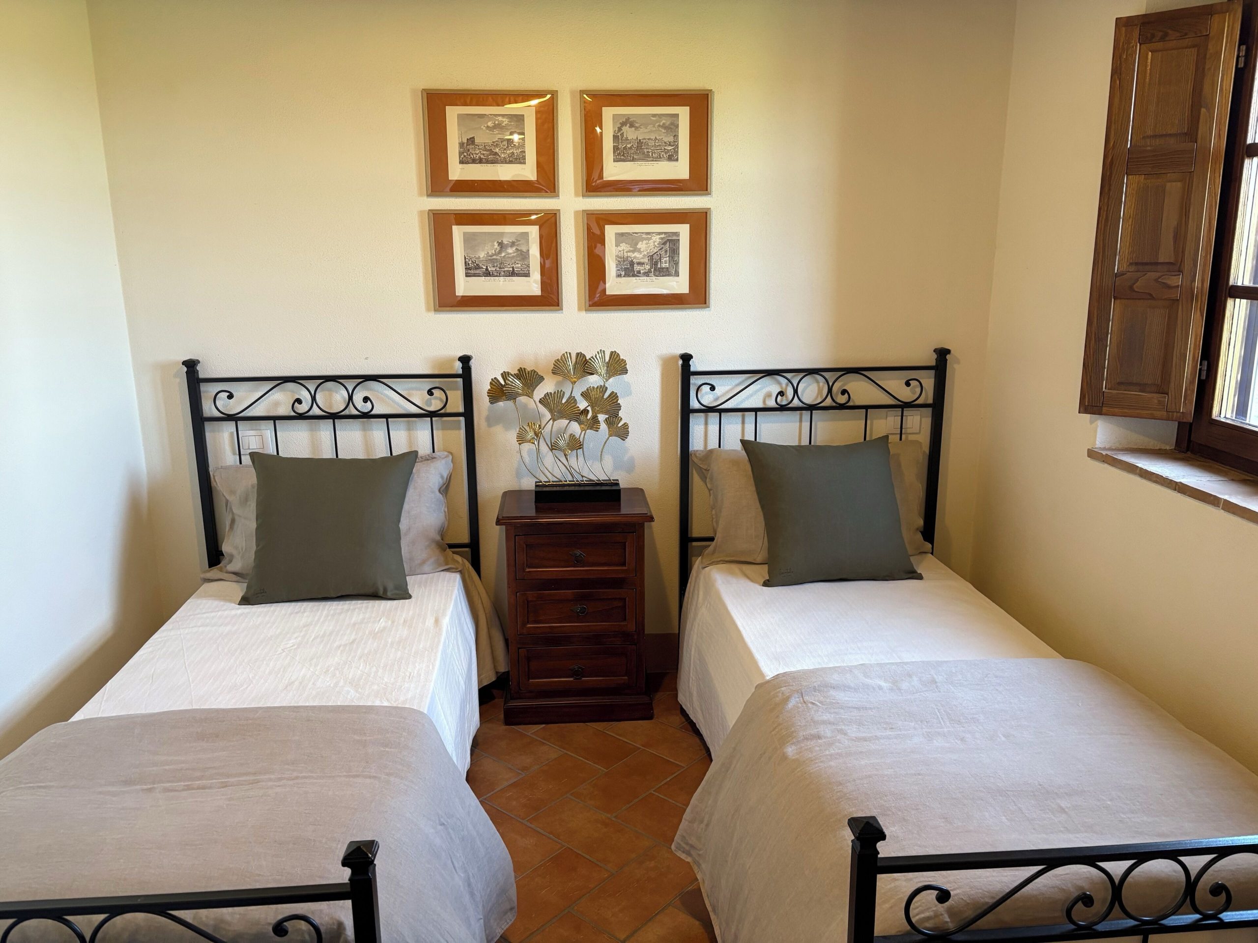 Twin Bedroom set up with two separate twin beds. Authentic tuscan tile flooring and a double casement window.